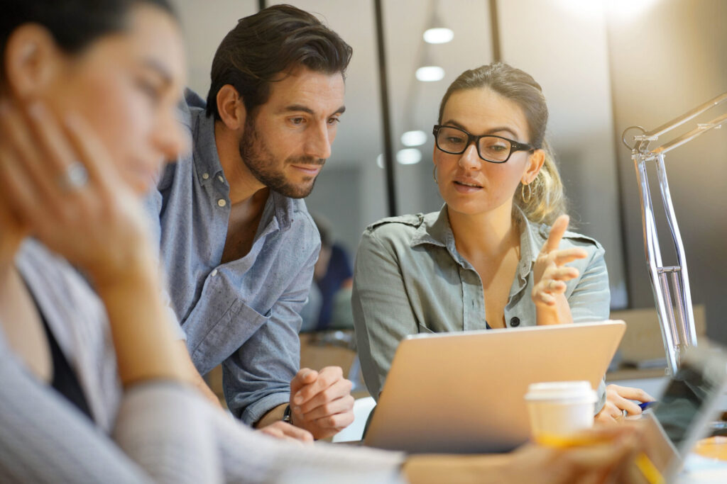 Co-workers talking in front of laptop