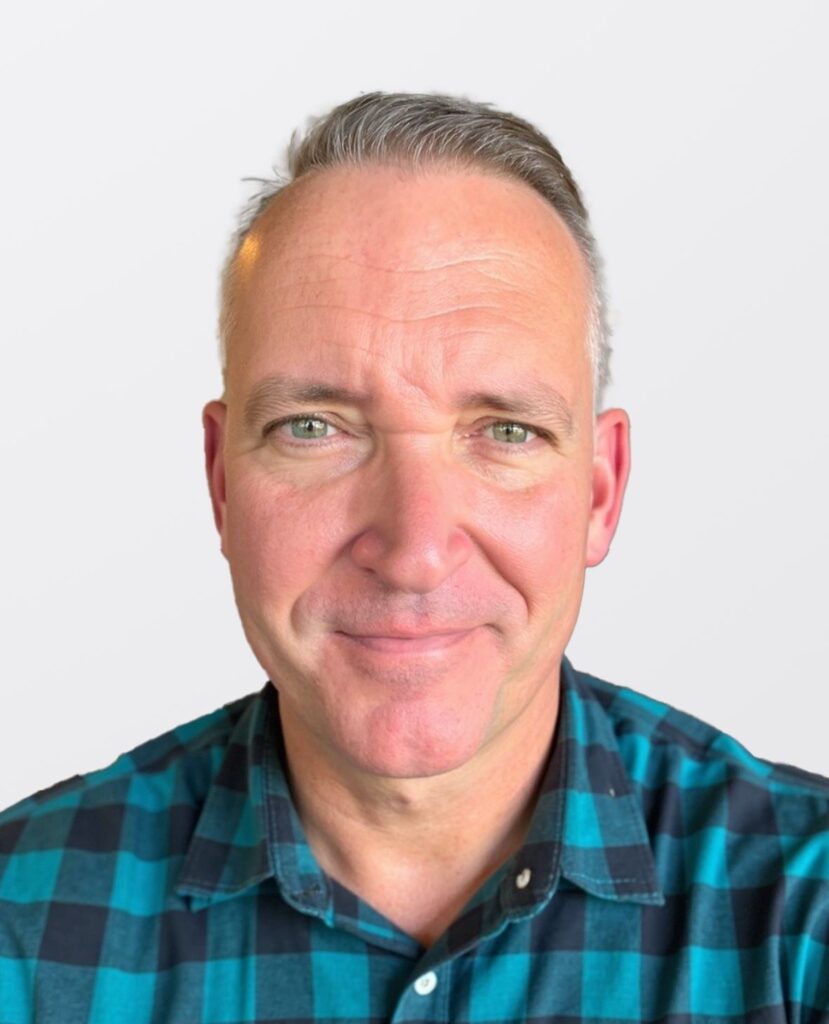 Smiling man in a plad shirt.